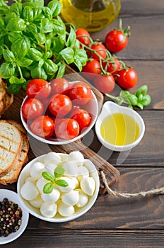 Italian food ingredients Ã¢â¬â mozzarella, tomatoes, basil and olive oil on rustic wooden table.